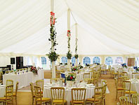 Poles in traditional style marquee garlanded with flowers