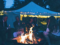 Sitting round a firepit with a lit up traditional tent in the background